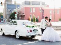 Bride and groom kiss in front of a white retro getaway car