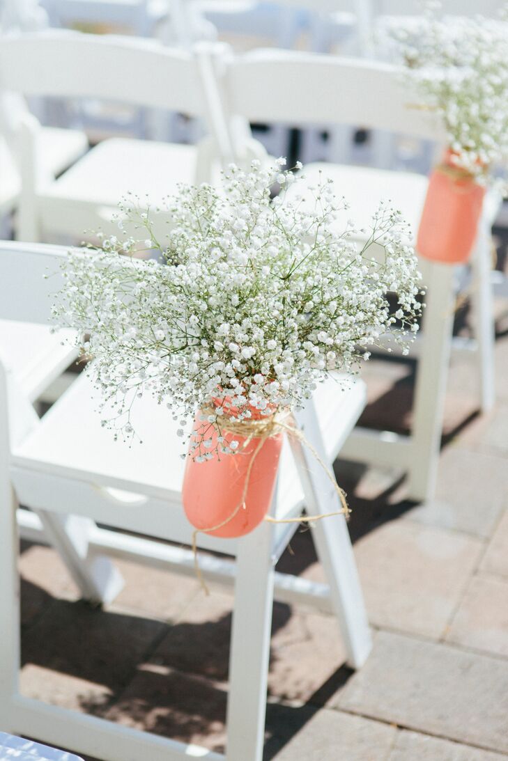 The outdoor ceremony took place at Aspen Lakes Golf Course in Sisters, Oregon, where white folding chairs faced the altar. Hanging bottles painted coral filled with baby's breath lined the aisle.