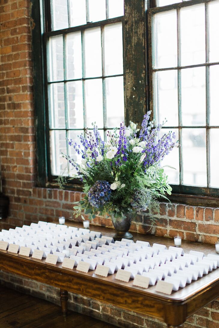 The DIY escort cards were displayed on a vintage brown table next to a lush floral arrangement and candle votives.