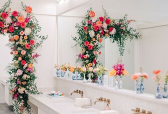 wedding venue bathroom decorated with pink flower arch, flowers in blue vases on the counter and small wedding bathroom basket