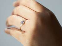 Round-cut diamond engagement ring with pear-shaped side stones on yellow gold band