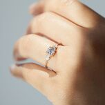 Round-cut diamond engagement ring with pear-shaped side stones on yellow gold band