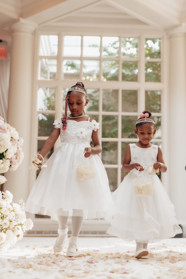 Flower Girls in White Dresses and Crowns Dropping White Petals Down Aisle With White Decor