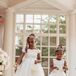 Flower Girls in White Dresses and Crowns Dropping White Petals Down Aisle With White Decor