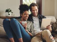 Couple smiling together on sofa using conversation starters 