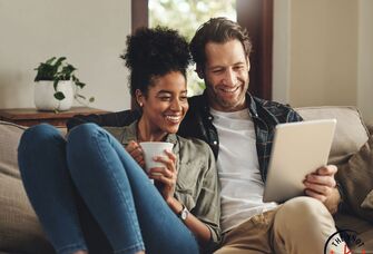 Couple smiling together on sofa using conversation starters 