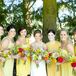 The bride stood with her bridesmaids dressed in a variety of yellow dresses, each holding a colorful bouquet of flowers.