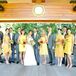 The bride and groom stood with their wedding party, who were dressed in gray or yellow attire.