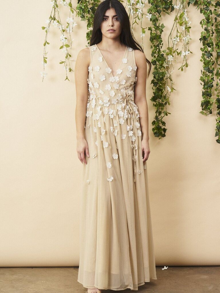 Model wears a cream and white maxi dress with floral detailing. 