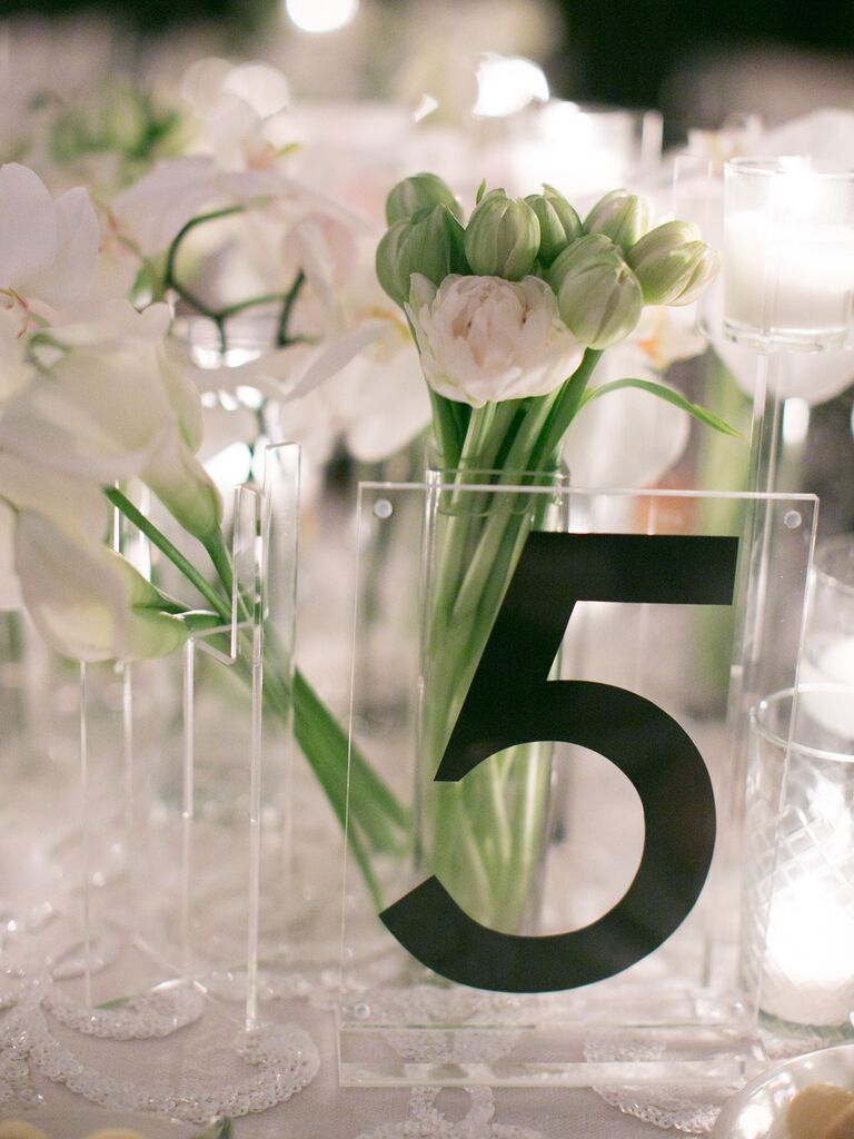 square acrylic wedding table number sign with the number 5 in black typography and simple white flower centerpiece