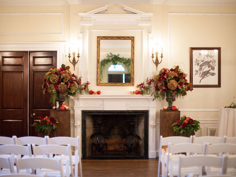 fall wedding fireplace decor with brown hydrangeas, red roses and red apples decorating the mantel
