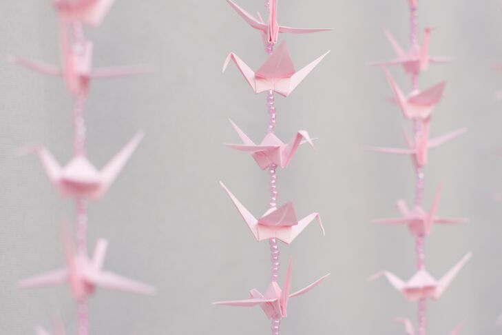 As a nod to her Japanese heritage, Kathleen incorporated 1,000 hand-folded origami cranes into the decor. In the months leading up to the wedding, her mother handcrafted each of the origami creations, then strung them onto a string with shimmering beads for the couple to use as their photo booth backdrop.