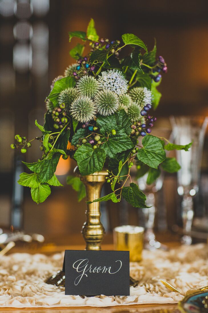 Arrangements of Scottish thistle, greens and hypercium topped brass candlesticks at the reception.