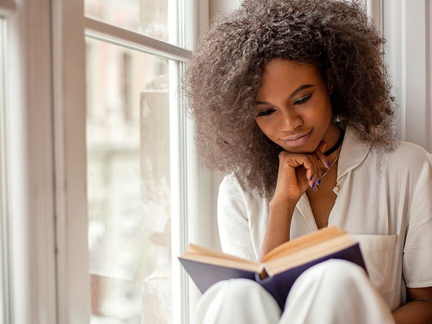 Woman sitting by window reading
