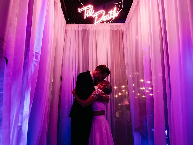 Couple kissing underneath neon sign