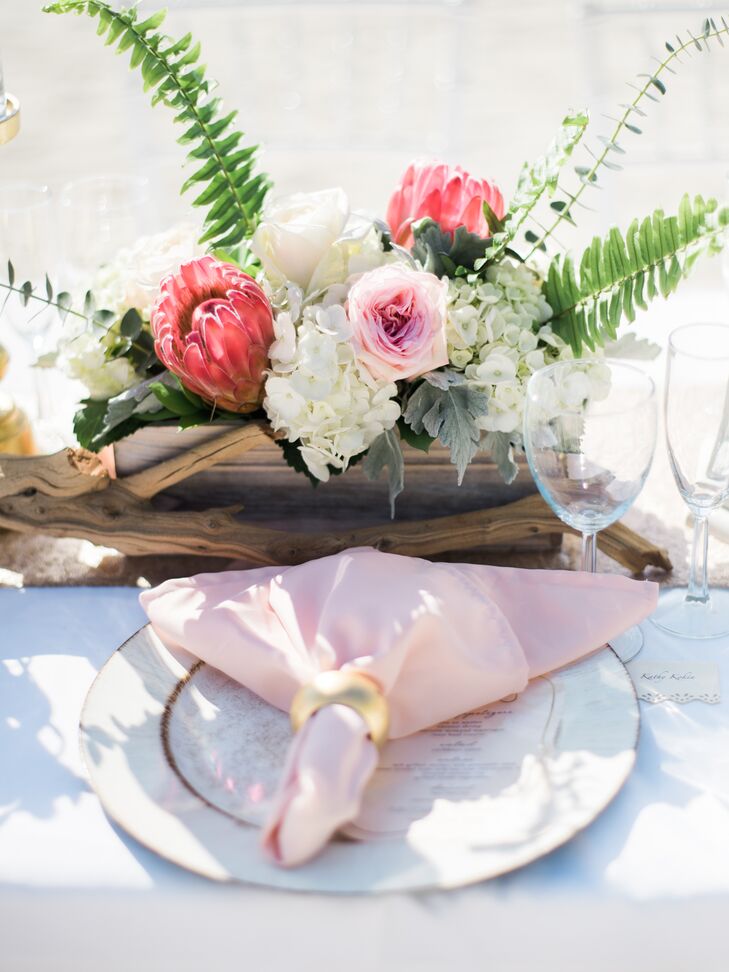 "I had menus printed that matched my invitations, which sat at each place setting. The florist worked her magic with wooden boxes filled with beautiful flowers and gold candle pillars," Nicole says.