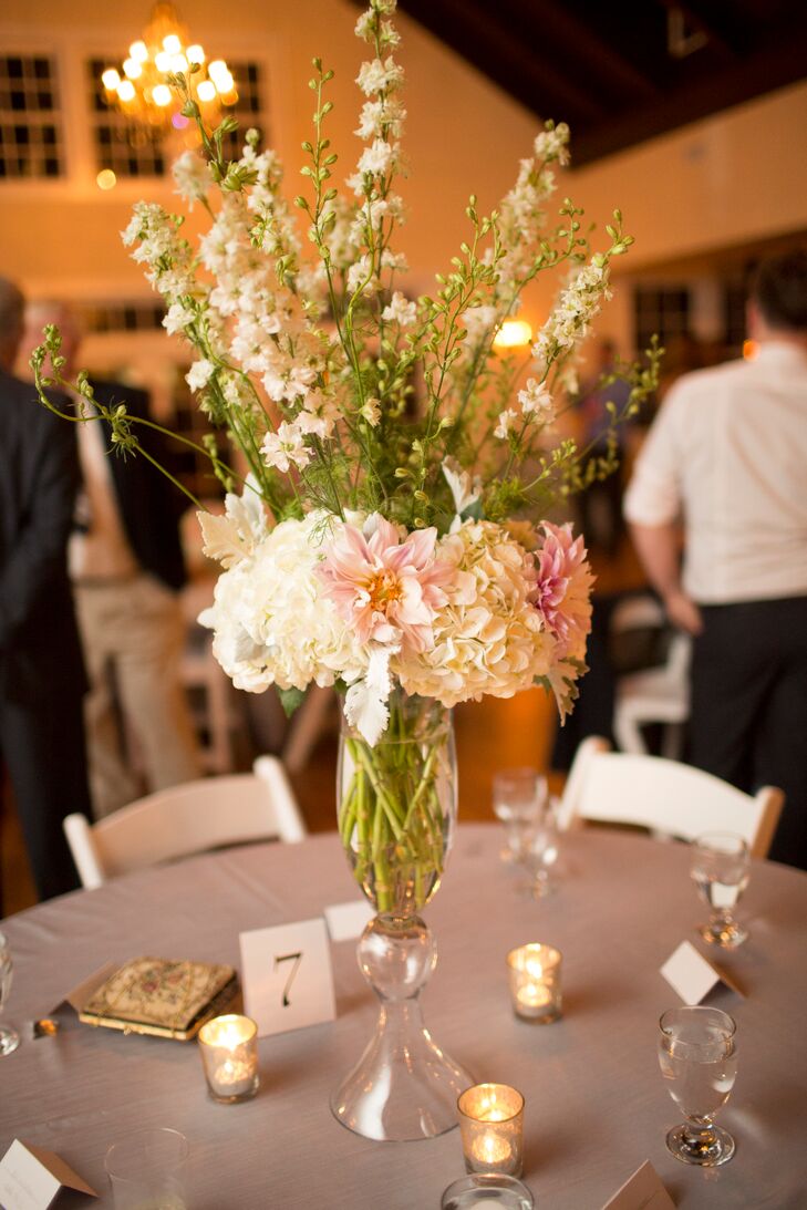 Centerpieces at the Portsmouth wedding included white hydrangeas, light pink dahlias and white delphiniums with sprigs of dusty miller in glass trumpet vases.