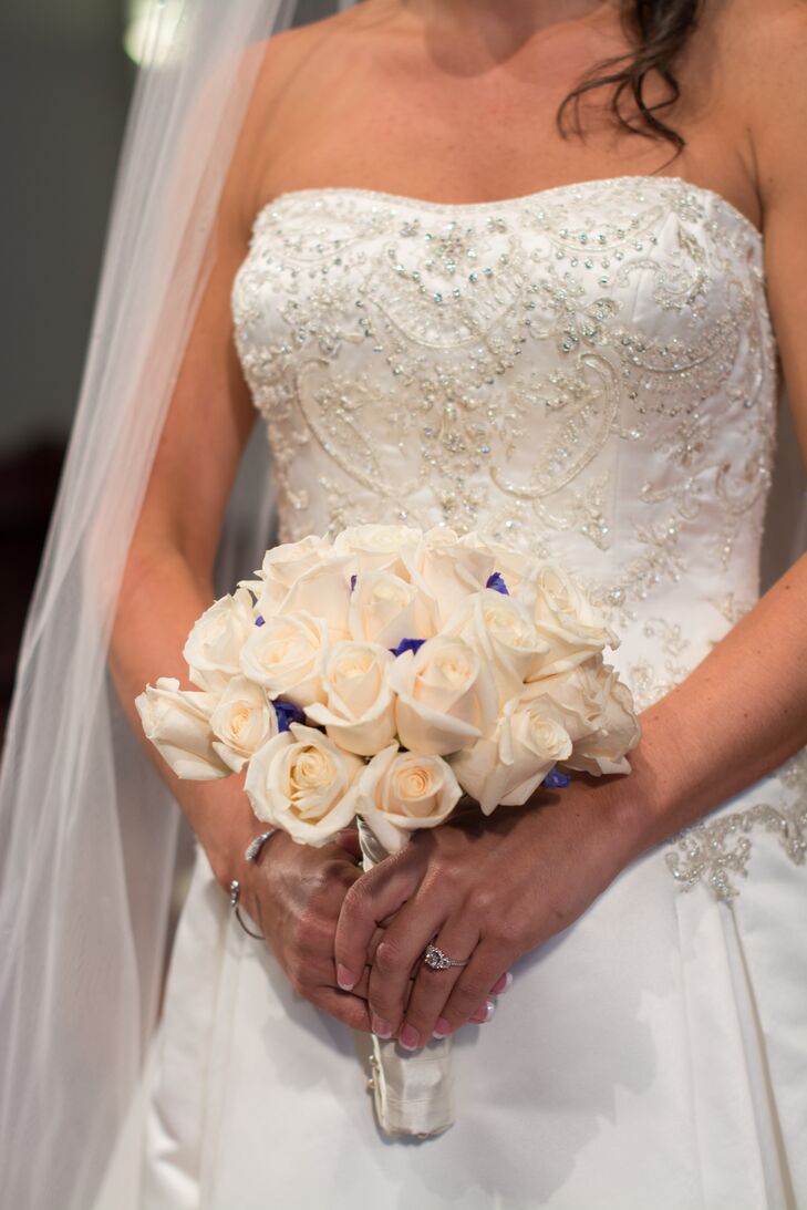 Pops of electric blue delphiniums added color to the bride's white rose wedding bouquet. rn