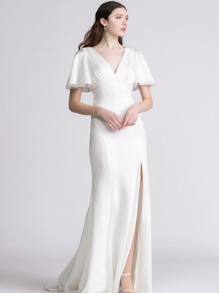 Model wears an elegant white silk dress with fluttery sleeves. 
