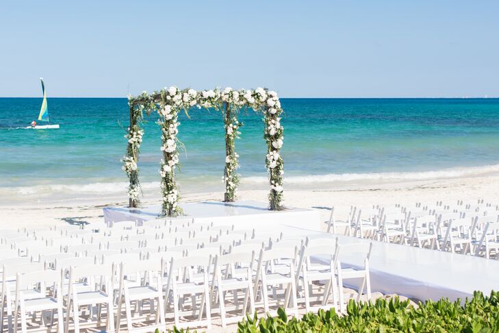 Michelle and Vincent said their vows under a four-post wedding arch made with twists of greenery  and white blossoms.
