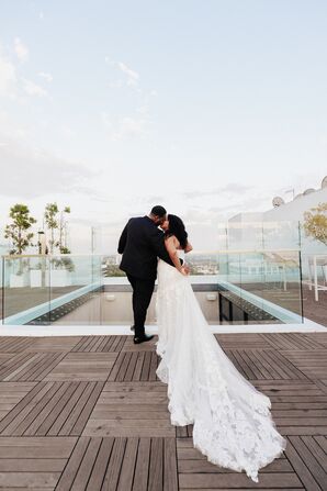 Groom Kissing His Bride With a Long Dress Train on Rooftop With Sky in Background