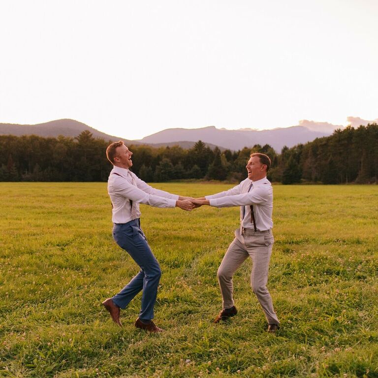 Couple twirling around in field at sunset