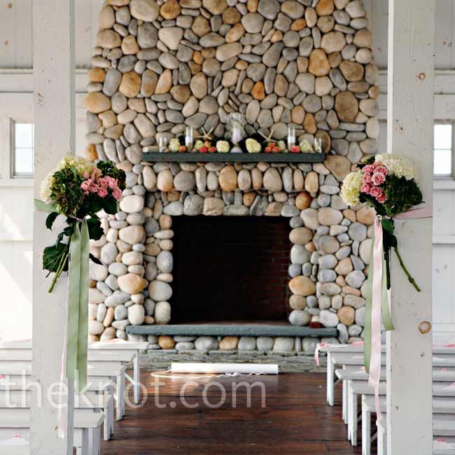 Two hand-tied bouquets of roses and hydrangeas marked the beginning of the aisle, which led to a fireplace decorated with white starfish, votive candles in sand, and fresh blooms.
