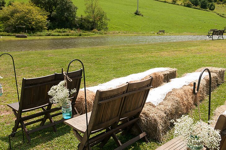 Mary and Sam's outdoor ceremony aisle was lined with blue glass mason jars filled with baby's breath and hanging from shepherd's hooks. Hay bales lined the outer edges of the ceremony chairs continuing the rustic look.