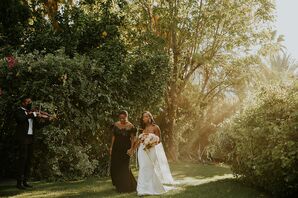 Bride's Mother in Chic Black Dress Leads Bride in Modern, Sleek Gown Down Garden Aisle Through Trees