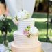 The couple served a three-tier ivory wedding cake decorated with pastel-colored flowers and displayed on a gold stand. “We adore a plethora of desserts, so it was hard to decide on just one,” the couple says. “They served a triple-tier, pink ombre-swirled cake with three flavors: raspberry cheesecake, pumpkin, and mocha fudge.”