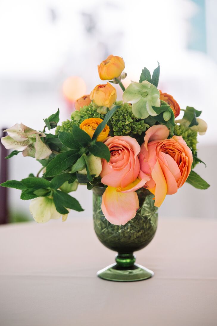 Caroline and Christopher's centerpieces brought in St. Augustine Green’s natural atmosphere with lush, natural arrangements. Events by Nouveau arranged each with greenery, green mini hydrangeas, peach roses, mustard yellow ranunculus and orange ranunculus inside a tall green pedestal vase.