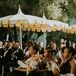 Guests in All Black Outfits, Bridesmaids With Colorful Bouquets Sit at Ceremony Under Bright Umbrellas
