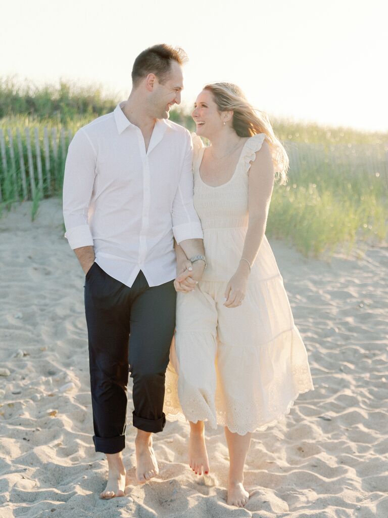 Couple looks at each other smiling on a beautiful beach. 