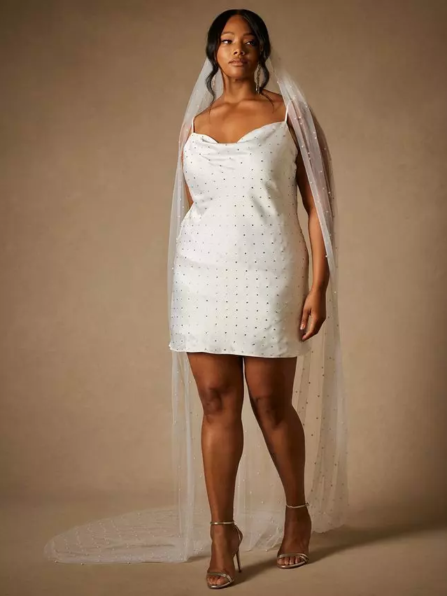 A model wears this beautiful retro-inspired thigh-high white dress with a cowl neckline.