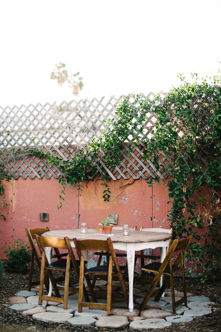 At the backyard reception, folding chairs were arranged around wooden tables, with simple decorations of succulents and candles. "For guest seating and tables, we brought in beautiful wooden wine barrels and vintage wooden tables," Emily says. "Market lights and steel heat lamps adorned the space, creating an uber-urban yet rustic atmosphere."