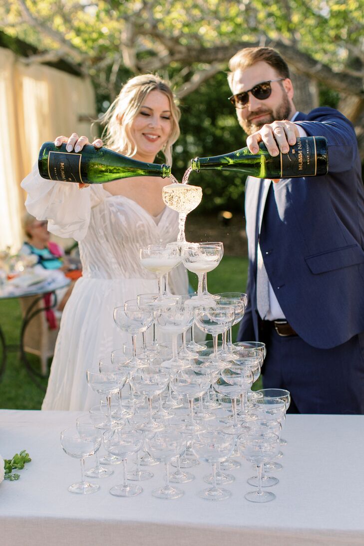 Bride and Groom Pour Champagne on Tower of Champagne Glasses