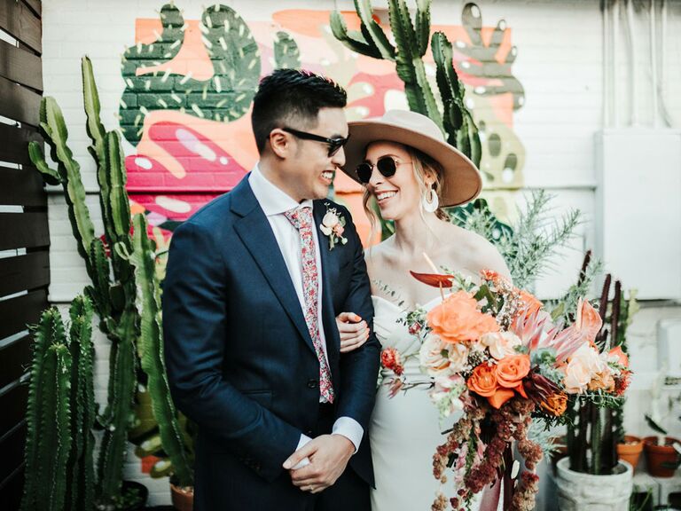 Bride and groom posing in front of succulents at boho-themed wedding