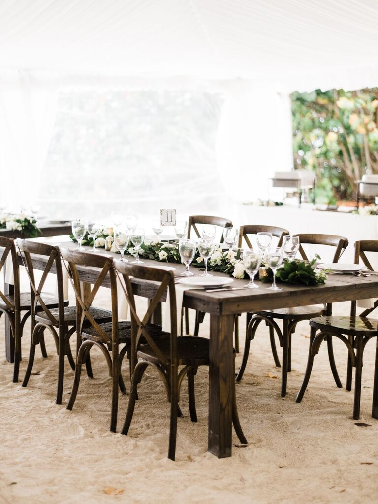 simple wooden wedding reception table with greenery runner