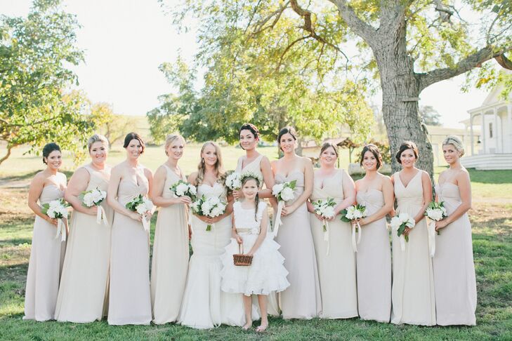 The bridesmaids followed the soft neutral-colored palette with their long dresses in different shades of white. They all held bouquets filled with white blooms and greenery, just like the bridal bouquet.