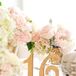Table numbers were gold cutout markers surrounded by delicate roses and baby's breath. Small votive candles highlighted each table.