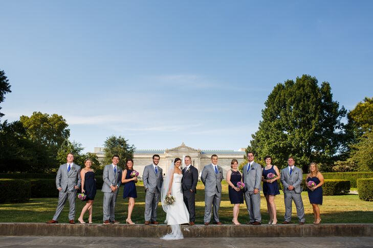 Jackie and Bryan stood in line with their wedding party, who dressed in light gray and purple attire that matched the day's palette. The groomsmen wore light gray shades designed by JoS. A. Bank, with navy blue ties and pocket squares that matched the short  bridesmaid dresses.