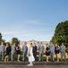 Jackie and Bryan stood in line with their wedding party, who dressed in light gray and purple attire that matched the day's palette. The groomsmen wore light gray shades designed by JoS. A. Bank, with navy blue ties and pocket squares that matched the short  bridesmaid dresses.