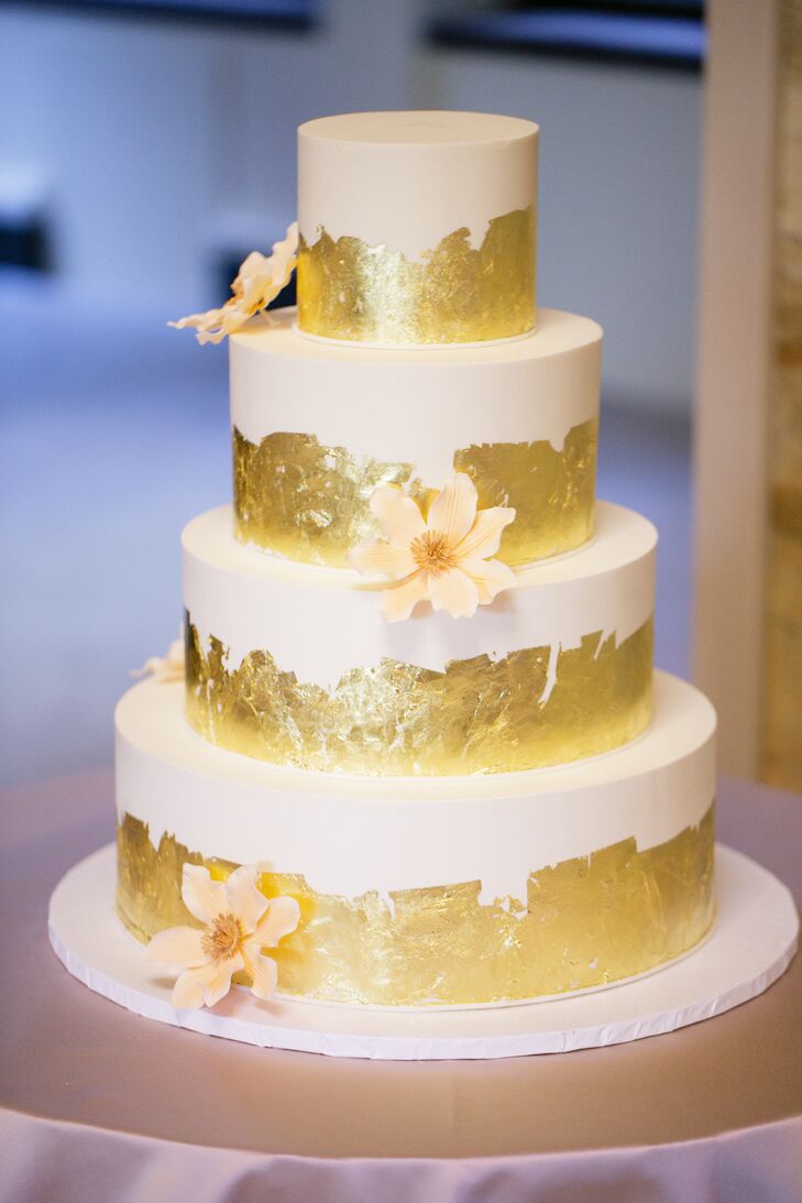 The wedding cake was a gilded four-tier confection with gold leaf detailing and ivory sugar flowers on each layer. Beneath the ivory buttercream frosting were three distinct flavors including vanilla sponge cake with heath bar filling, chocolate pound cake with butterscotch filling and chocolate sponge cake with pecan cookie dough.