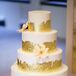 The wedding cake was a gilded four-tier confection with gold leaf detailing and ivory sugar flowers on each layer. Beneath the ivory buttercream frosting were three distinct flavors including vanilla sponge cake with heath bar filling, chocolate pound cake with butterscotch filling and chocolate sponge cake with pecan cookie dough.