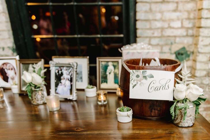 Guests placed cards inside the wooden barrel marked with a watercolor design, positioned next to family photos in vintage frames, mercury glass votive candles and tiny potted succulents.