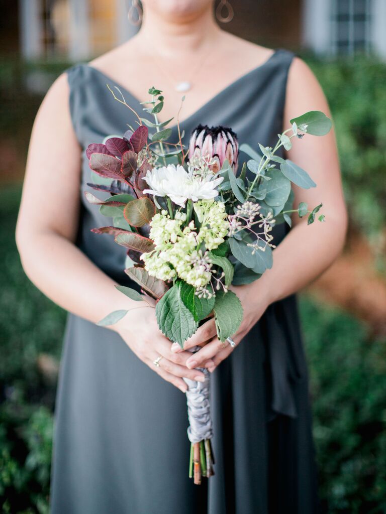 A bridesmaid holds this winter-toned floral bouquet.