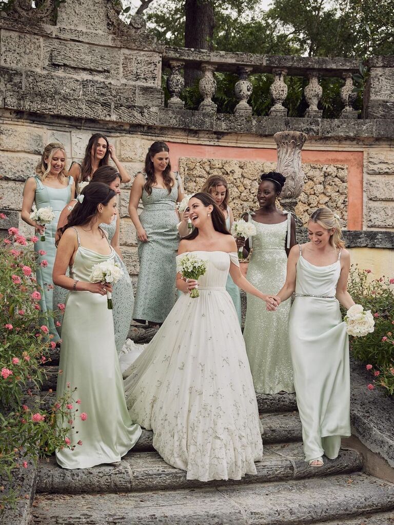 Bride and bridesmaids pose on the steps in a beautiful park. 