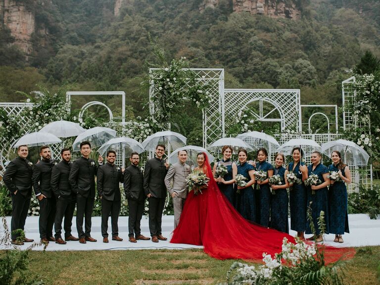Wedding party poses with umbrellas on a rainy day. 