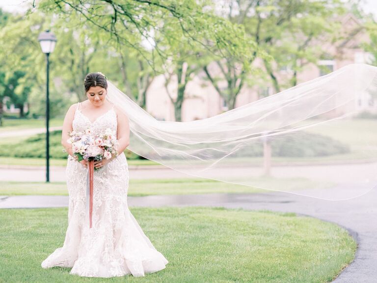 Bride posing with long veil blowing in the wind
