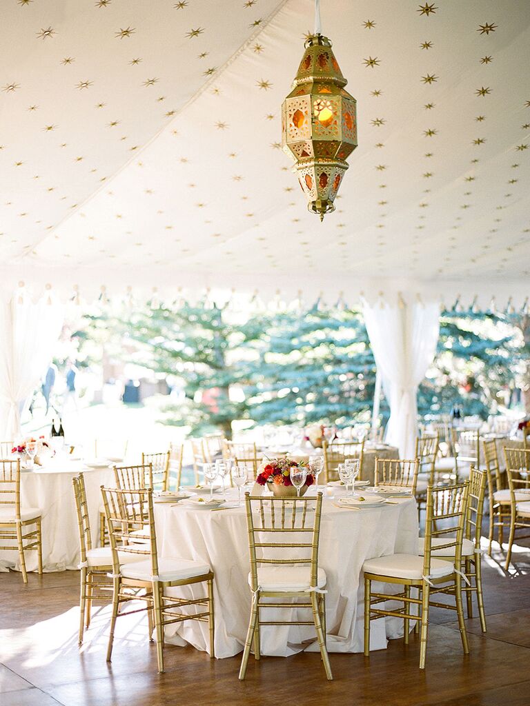 Round reception tables with gold chairs in tent